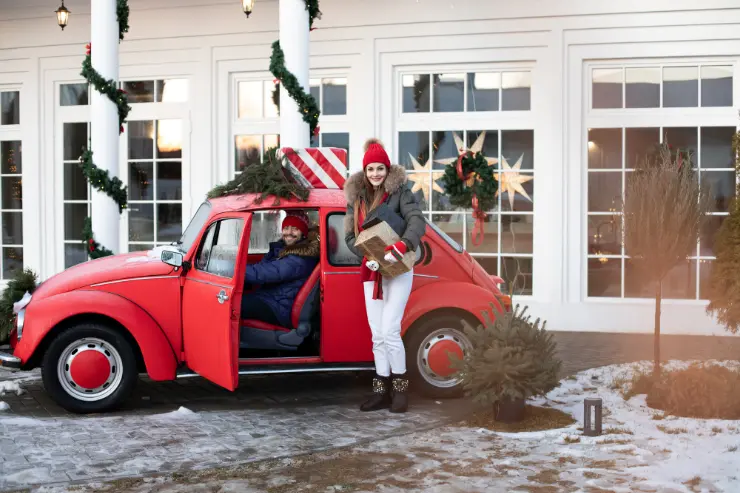 Coche rojo con una pareja en un entorno navideño