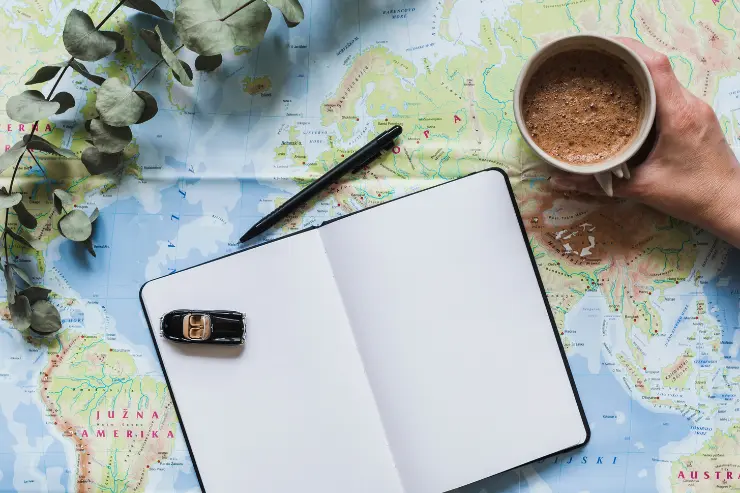 plano-coche-cafe Mesa con una libreta y cafe para planificar el viaje